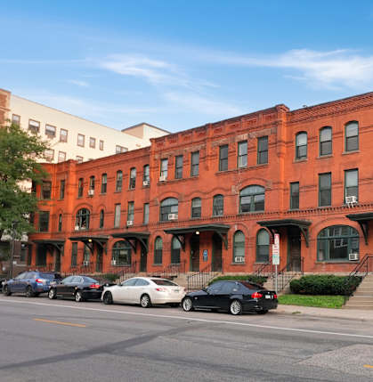 A red brick building with a black car parked in front.