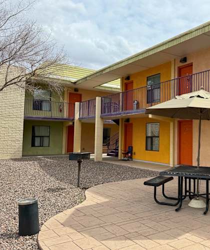 A patio with a table and chairs is in front of a building with orange doors.
