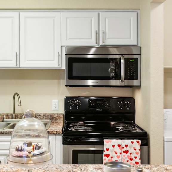 A kitchen with a black stove and white cabinets.