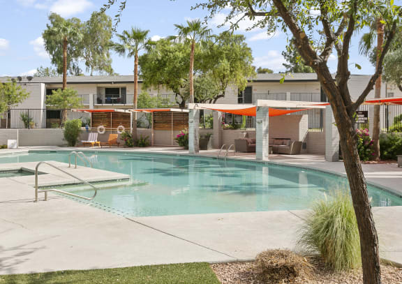 Sentry Apartments' swimming pool features clear blue water, a concrete patio, lounge chairs, and shaded orange cabanas.