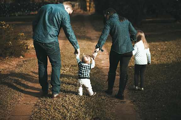 A family of three are walking down a path holding hands.