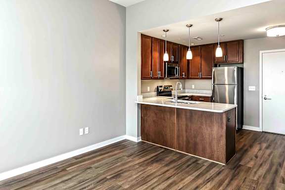 U-shaped kitchen with warm dark brown cabinets and pendant lighting