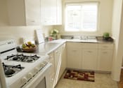 Thumbnail 8 of 22 - A kitchen with a white stove and white cabinets.