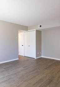 an empty living room with wood floors and white walls
