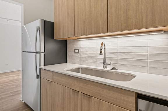 A kitchen with a white sink and a white refrigerator.