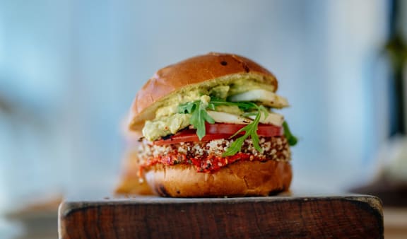 a hamburger sitting on top of a wooden plate