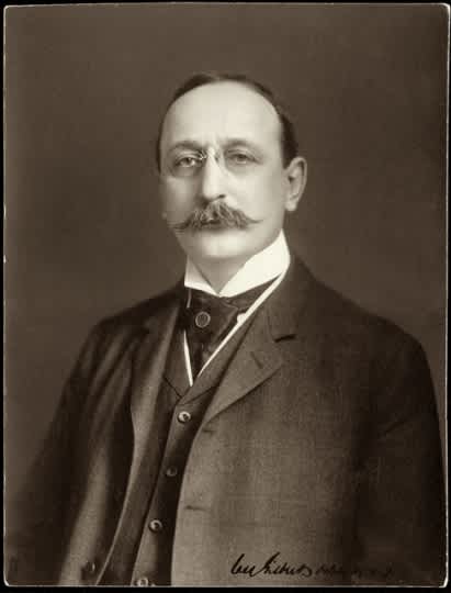 A man with a mustache and wearing a suit is posing for a photo.