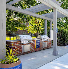 A white pergola is over a patio with a grill and chairs at Jamison Park Apartments in North Charleston, SC 29406