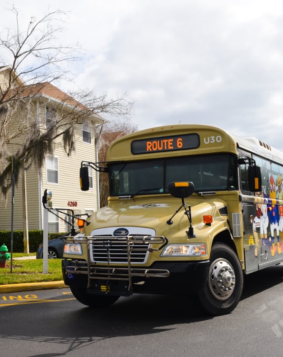 a school bus parked on the street in front of a house at Tivoli Apartments of Orlando, Oviedo, Florida, 32765