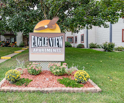 the sign for eagle view apartments in front of a yard with flowers