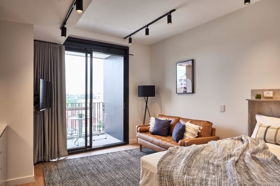 a bedroom with a couch and a bed and a sliding glass door