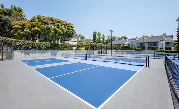 A tennis court surrounded by trees and buildings.