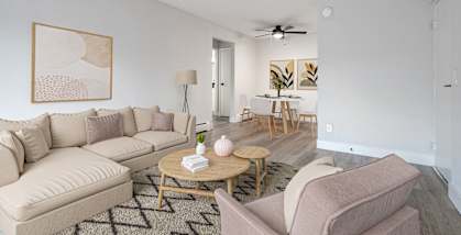 A living room with a beige couch, a coffee table, and a painting on the wall.