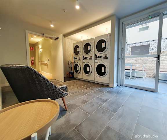 a washer and dryer area in a laundry room with a table and chair