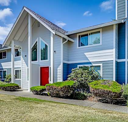 a row of apartments with blue siding and a red door