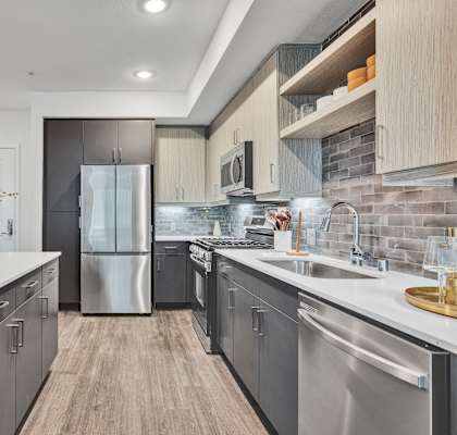 A modern kitchen with stainless steel appliances and wooden flooring.