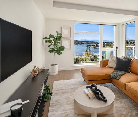 a living room with a leather couch and a television and a view of the water at Liza Apartments, Washington