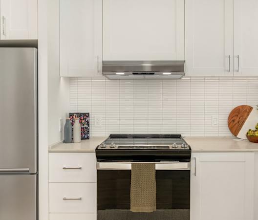 a kitchen with white cabinets and a stove and microwave at Liza Apartments, Washington