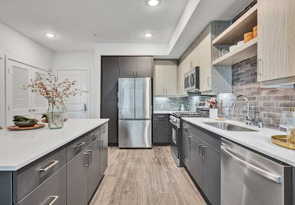 A modern kitchen with stainless steel appliances and wooden flooring.