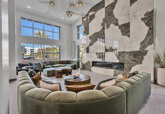 A large room with a green couch and a marble wall.