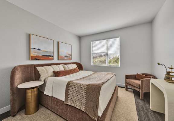 A bedroom with a large bed and two chairs.
