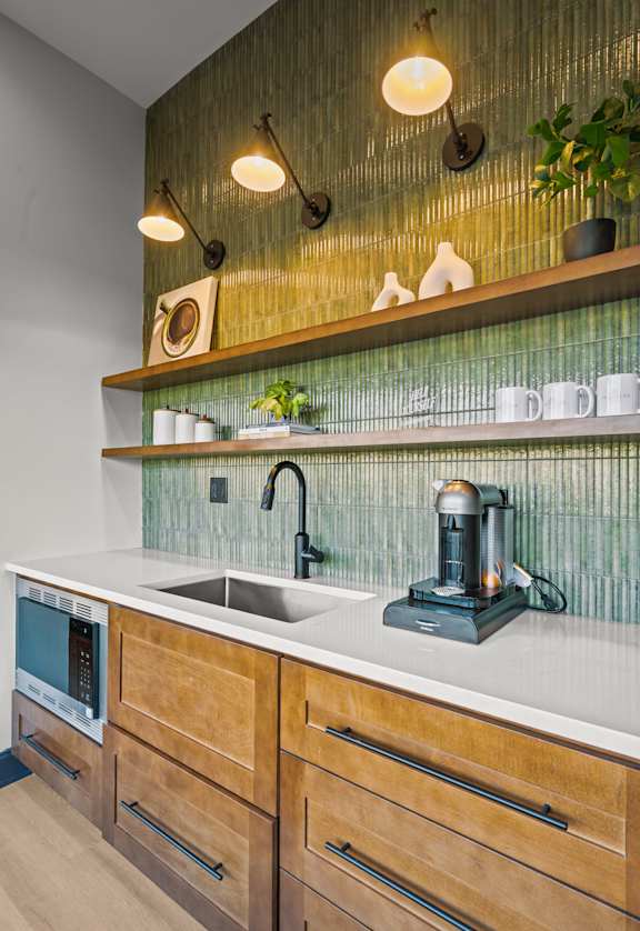 A modern kitchen with wooden drawers and a green backsplash.