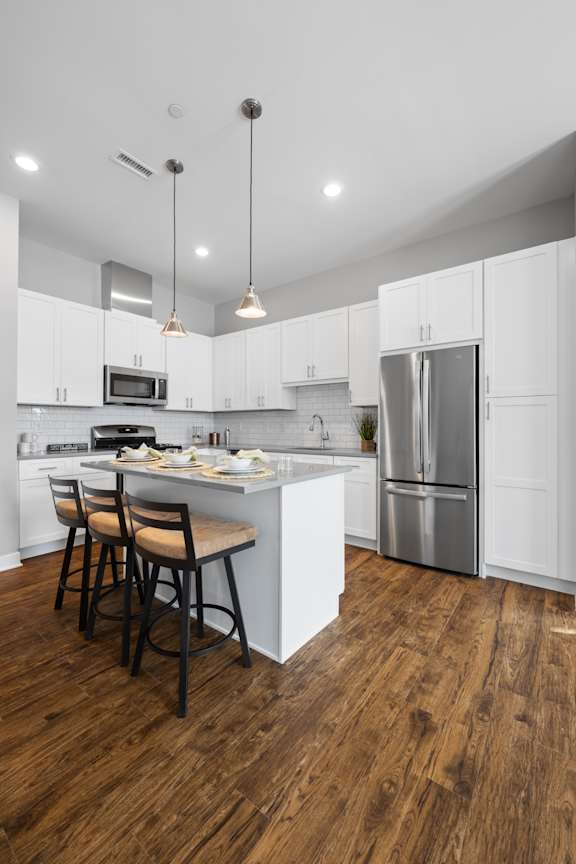 A modern kitchen with white cabinets and a wooden floor.