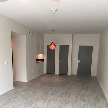 A room with grey flooring and a hanging light fixture.