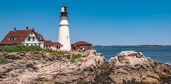 A lighthouse stands on a rocky shore.