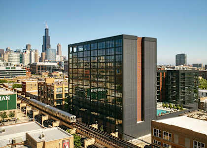 A train is on the tracks in front of a large building. at The Mason Apartments, Illinois, 60607