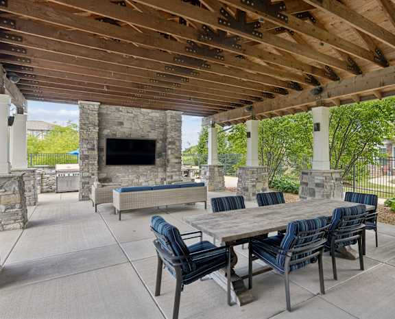 A patio with a table and chairs and a stone fireplace.
