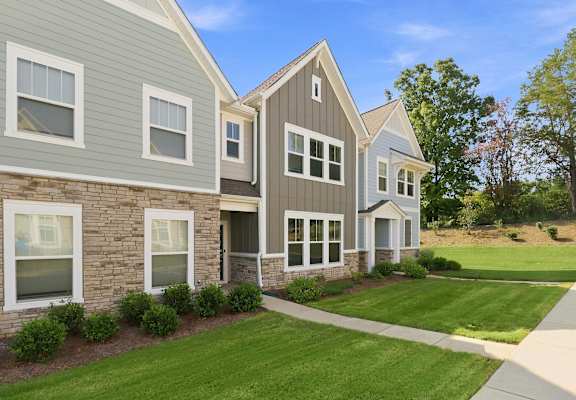 A row of houses with a green lawn in front.