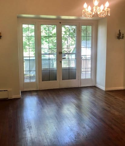 an empty living room with french doors and a chandelier