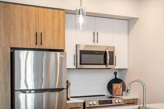 A modern kitchen with a white countertop and black chairs.at Vibe Apartments at Arbour Lake, Calgary, AB