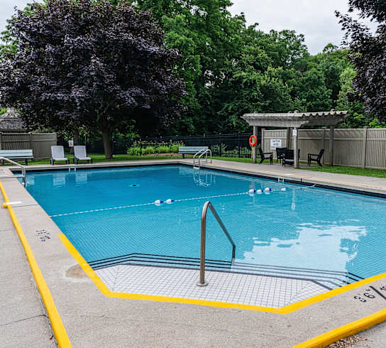 a swimming pool in a park with trees and a fence