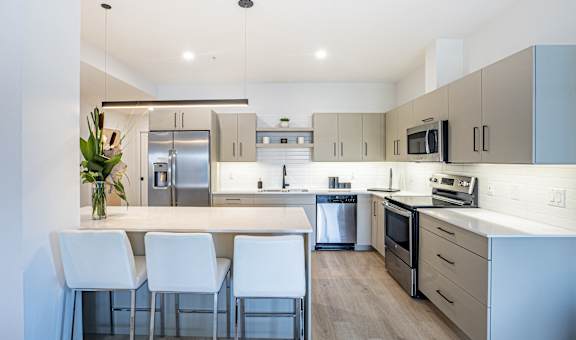 a modern kitchen with a large island with white chairs