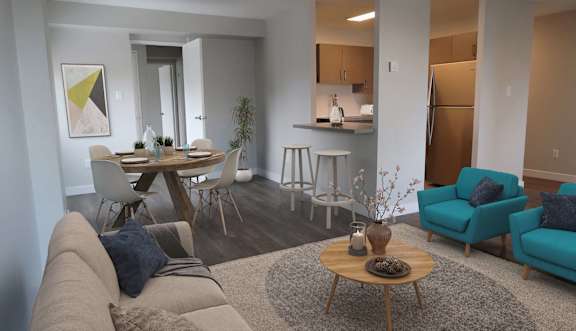 A living room with a grey sofa, a wooden coffee table, and a dining table set up in the background.