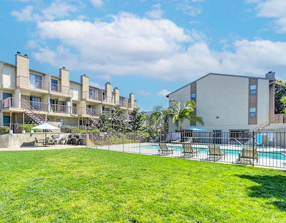 an apartment building with a lawn and a pool in front of it