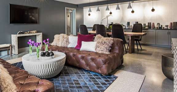 A modern living room with a brown leather sofa and a white coffee table.