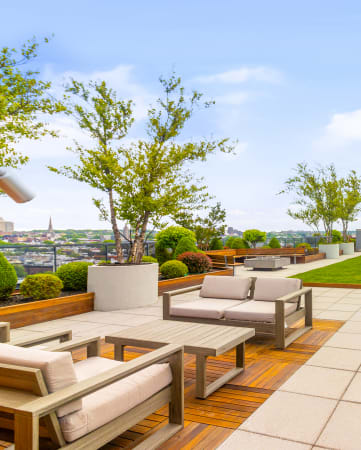 a roof top lounge with a grassy area and a view of the city