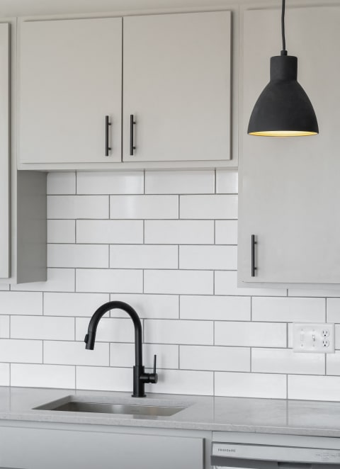 A black and white kitchen with white subway tiles and a black sink at Kesler Apartments in Downtown Fargo, Fargo, ND 58102