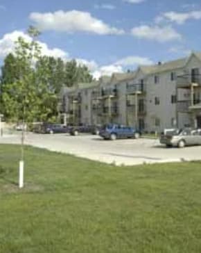 Apartment building with cars parked in front.