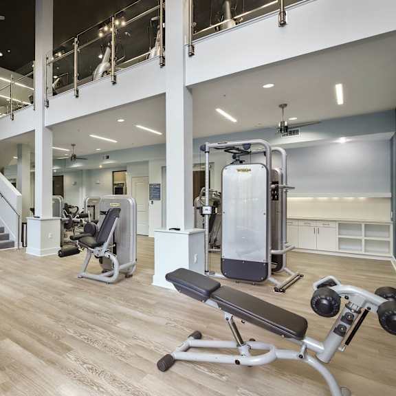 A gym with a variety of equipment including a treadmill, weights, and a bench press.
