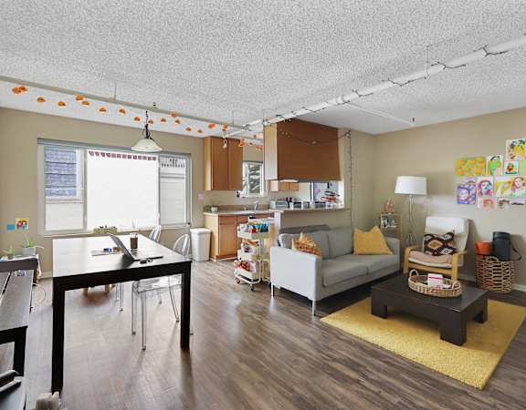 A living room with a couch, coffee table, and a dining table.