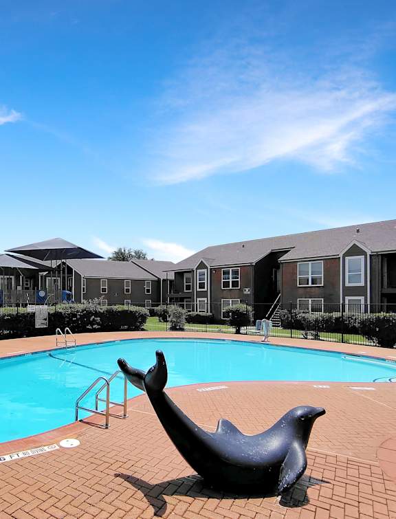 A pool with a seal statue in front of apartment buildings.