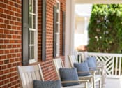 Thumbnail 4 of 31 - A row of rocking chairs with cushions are lined up on a porch.