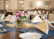 Thumbnail 8 of 31 - A dining table set with a napkin, glasses, and flowers.