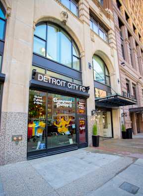 A Detroit City storefront with a black awning and glass doors.