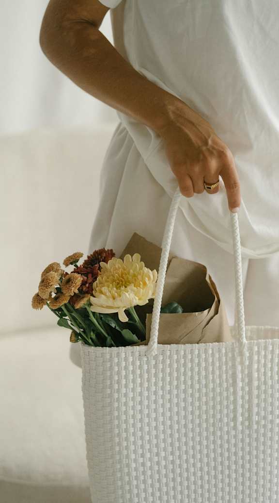 A person holding a white bag with flowers in it.