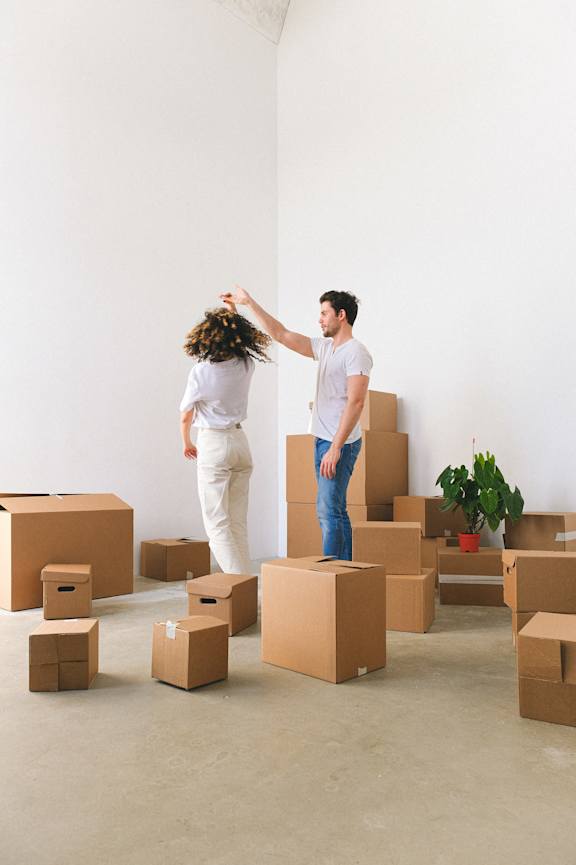 A man and woman dancing in a room surrounded by cardboard boxes.